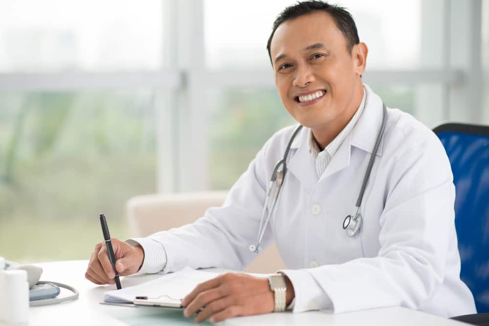 Doctor typing on laptop with stethoscope and paperwork